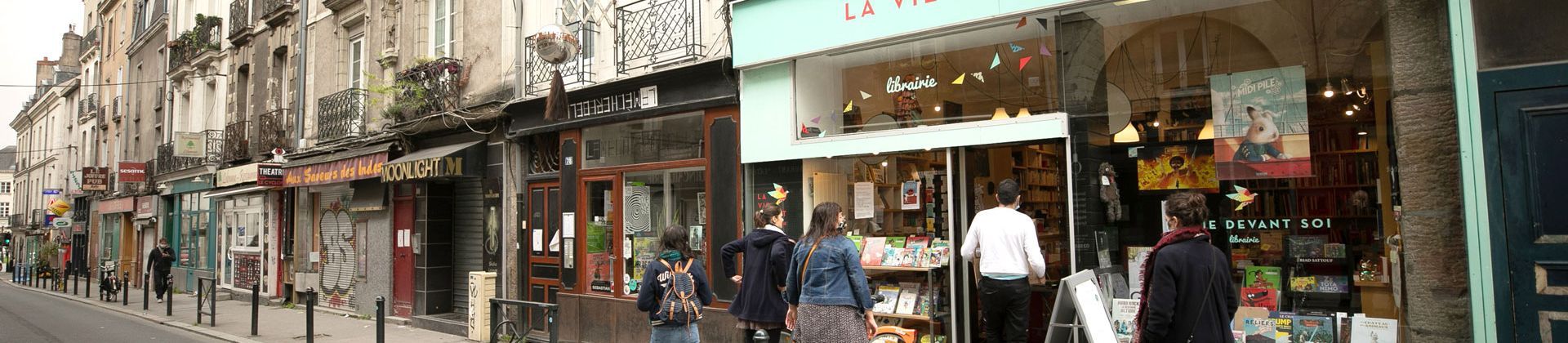 rue avec passants masqués devant une librairie ouverte