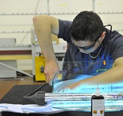 jeune homme avec lunette de protection penché sur son travail dans un atelier